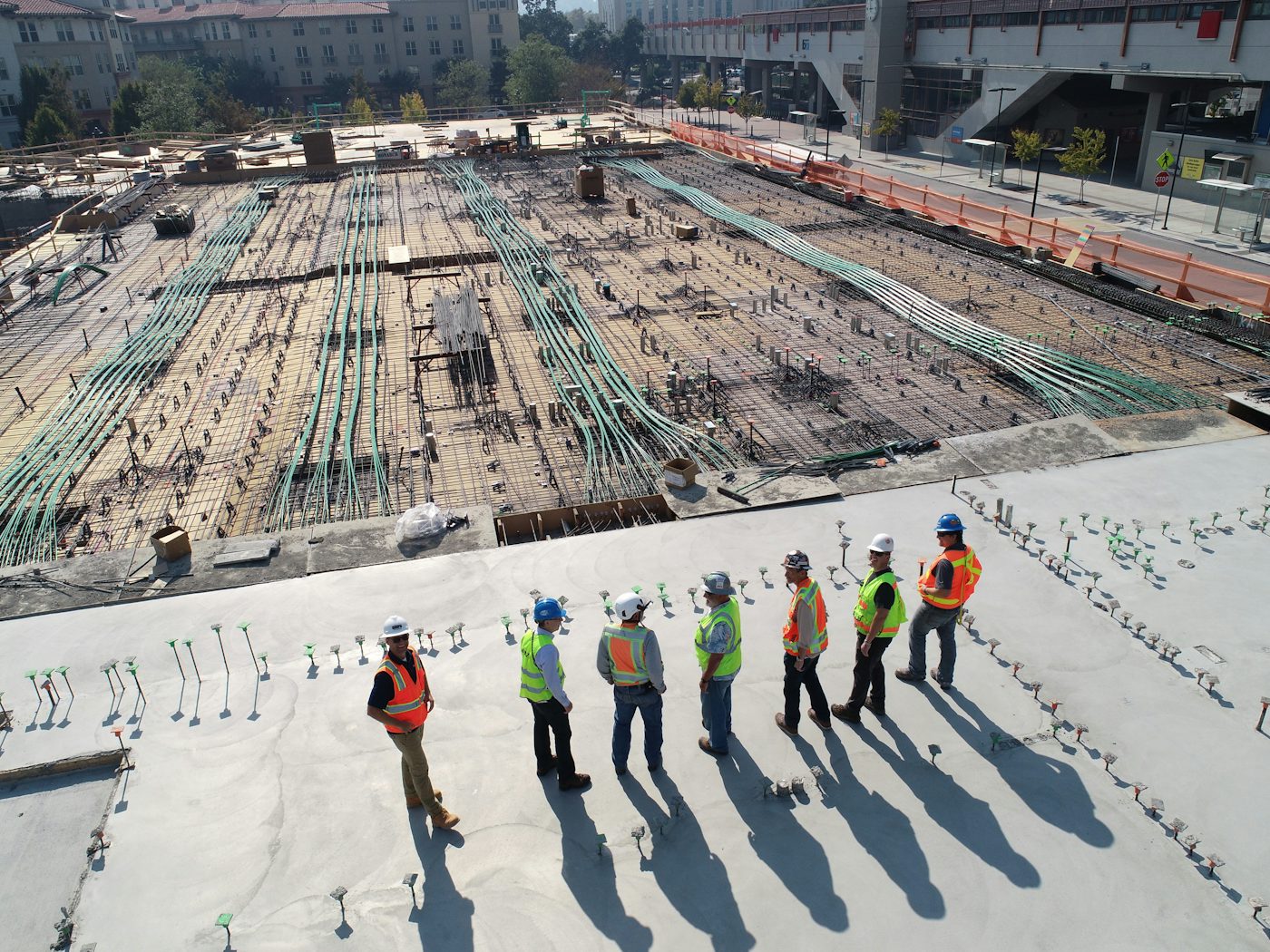 Project team in hard hats and safety vests walking a concrete deck during a site inspection