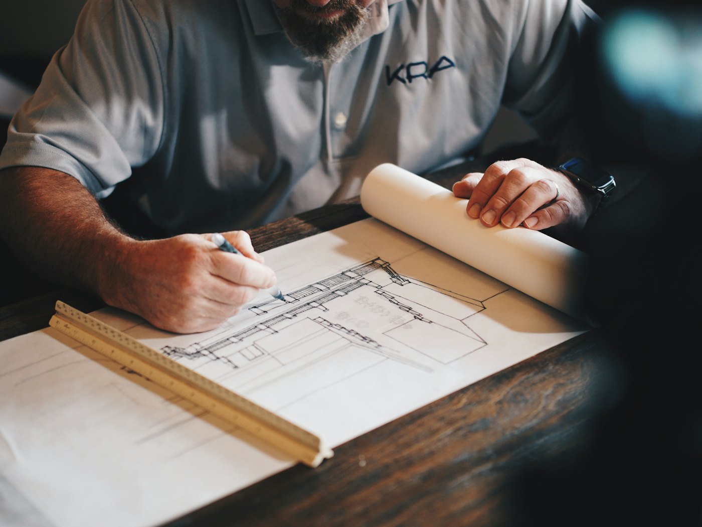 Estimator marking up a building elevation drawing with a scale ruler